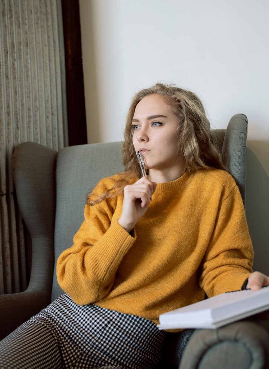 Personne en réflexion dans un fauteuil avec un carnet